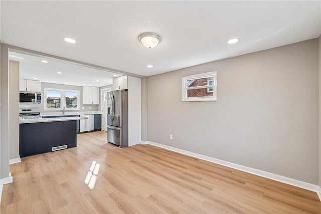 kitchen featuring stainless steel appliances, light countertops, white cabinets, and baseboards