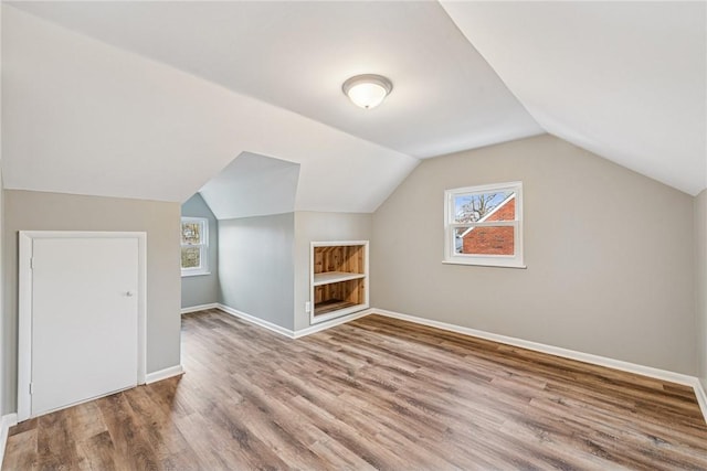 bonus room featuring lofted ceiling, wood finished floors, and baseboards