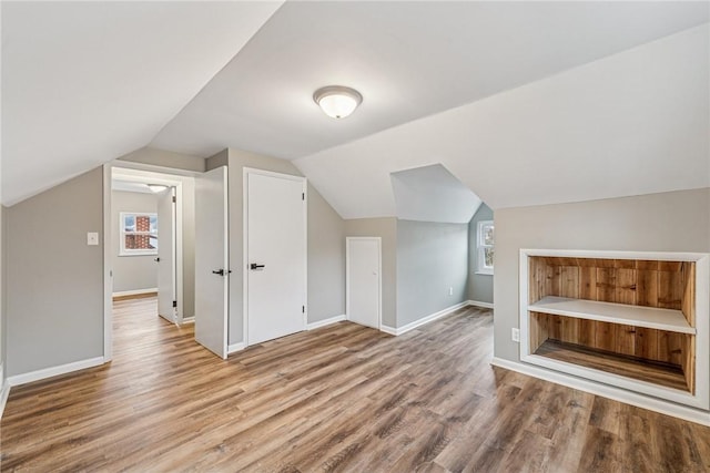 additional living space featuring baseboards, vaulted ceiling, and wood finished floors