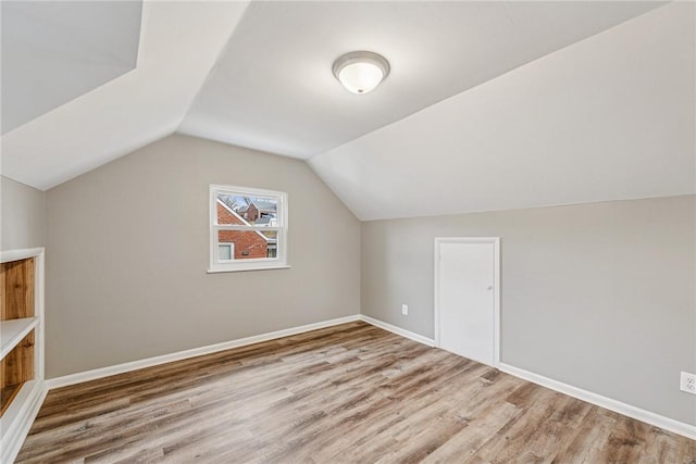 additional living space with vaulted ceiling, wood finished floors, and baseboards