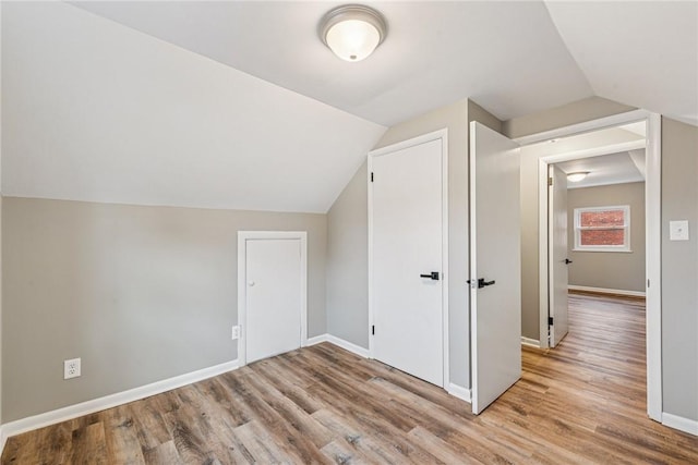 additional living space featuring lofted ceiling, baseboards, and wood finished floors