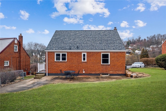 rear view of house featuring brick siding, a lawn, fence, and a patio