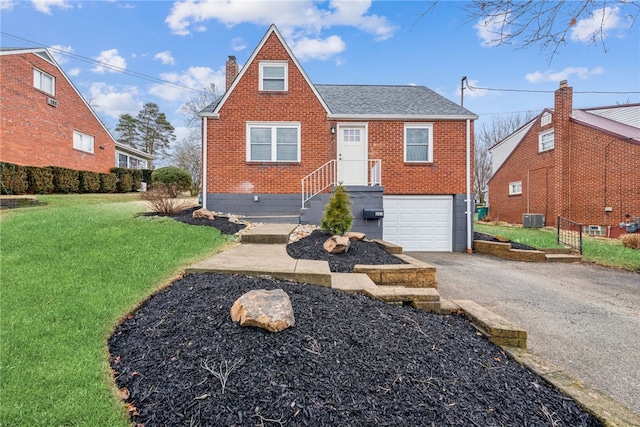 view of front of home with driveway, a garage, brick siding, central AC unit, and a front yard