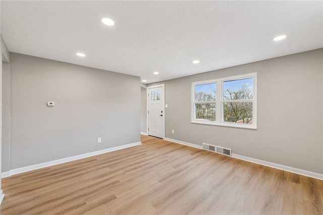 unfurnished room featuring light wood finished floors, recessed lighting, visible vents, and baseboards