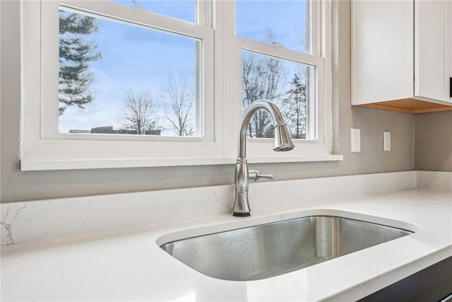 interior details featuring light countertops, a sink, and white cabinetry