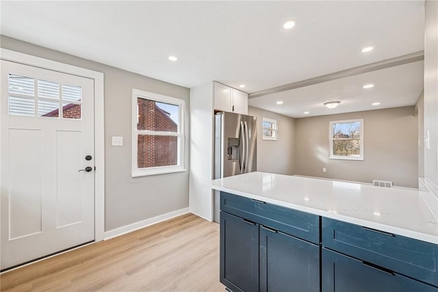 kitchen featuring light wood finished floors, visible vents, light countertops, a healthy amount of sunlight, and stainless steel refrigerator with ice dispenser