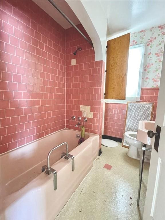 full bathroom featuring wallpapered walls, wainscoting, toilet, shower / bathtub combination, and tile walls