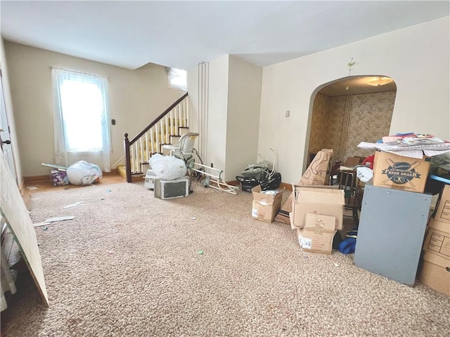 interior space featuring carpet floors, arched walkways, and stairs