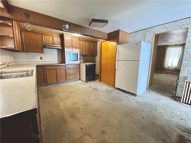 kitchen featuring white appliances, brown cabinetry, unfinished concrete flooring, light countertops, and a sink