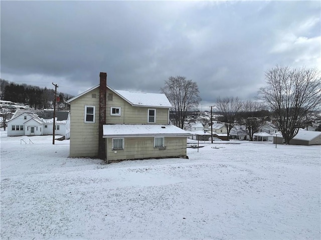 snow covered house featuring a chimney