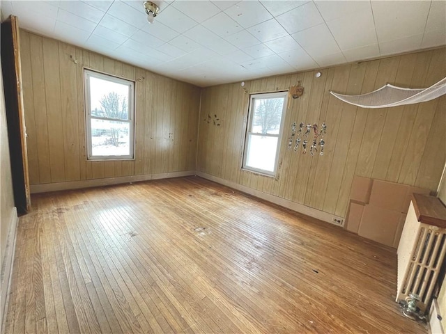 empty room with radiator, light wood-type flooring, and baseboards