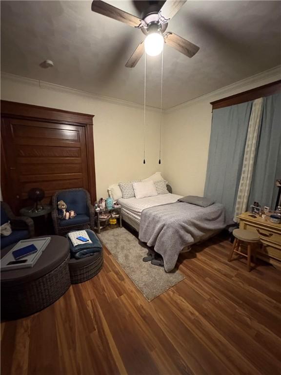 bedroom with ornamental molding, ceiling fan, and wood finished floors