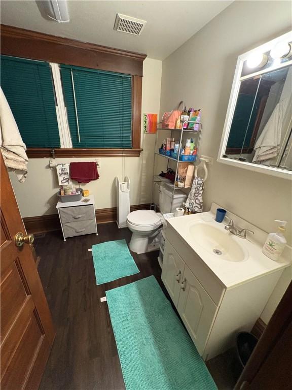 bathroom featuring baseboards, visible vents, toilet, wood finished floors, and vanity