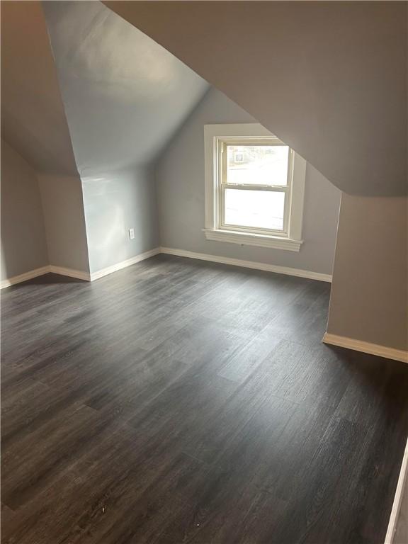 bonus room featuring lofted ceiling, dark wood-type flooring, and baseboards