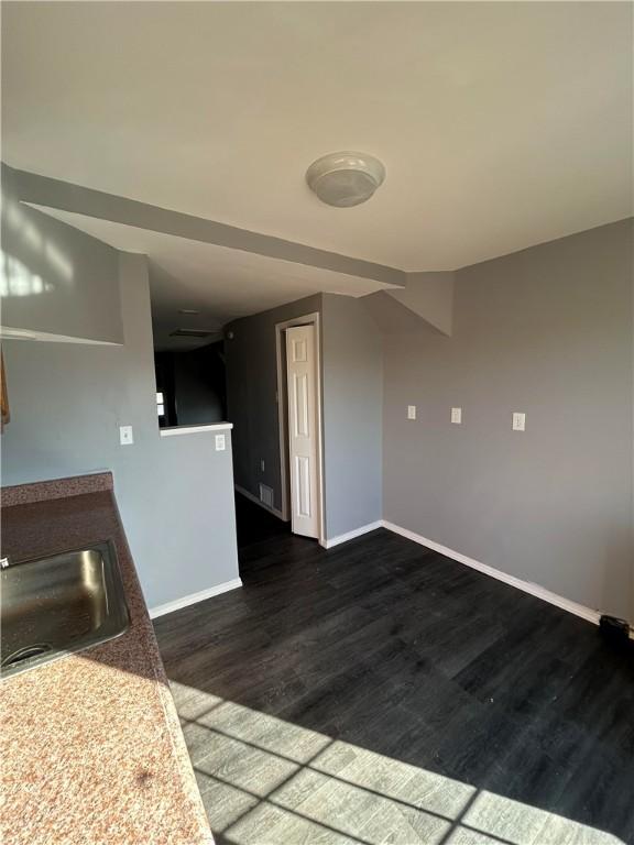 interior space with dark wood-type flooring, a sink, and baseboards