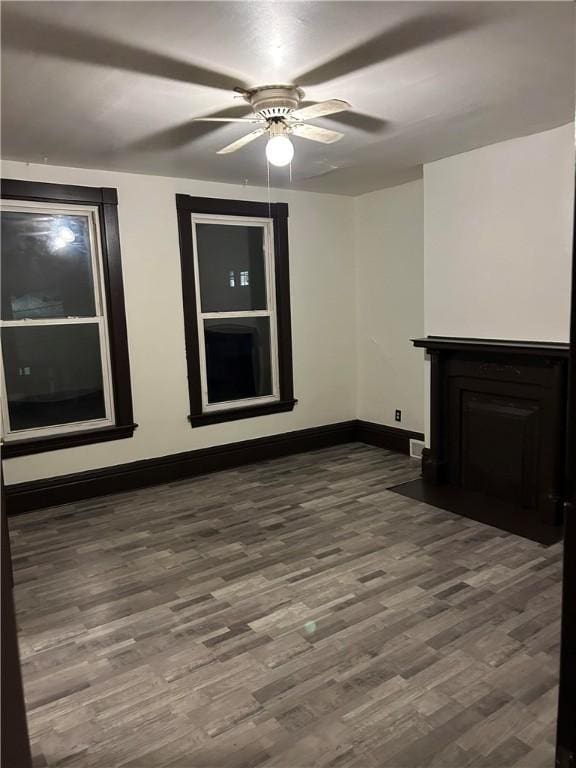 unfurnished living room with a ceiling fan, dark wood-style flooring, and baseboards