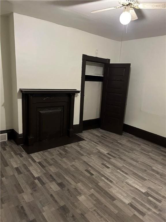 interior space featuring a fireplace with flush hearth, baseboards, and wood finished floors