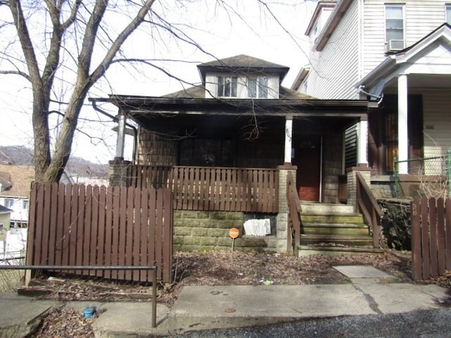 view of front of property with fence, a porch, and cooling unit