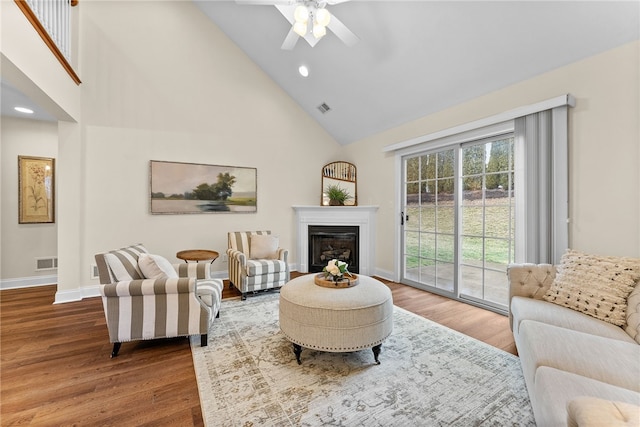 living area featuring visible vents, wood finished floors, and a glass covered fireplace