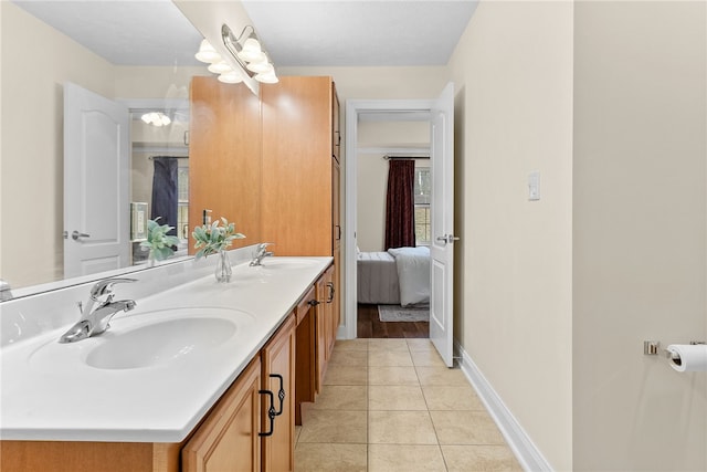 full bathroom featuring double vanity, baseboards, a sink, and tile patterned floors