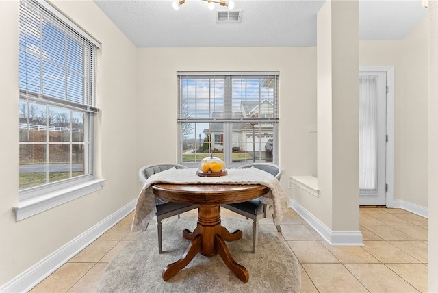 dining space with light tile patterned floors, baseboards, visible vents, and a textured ceiling