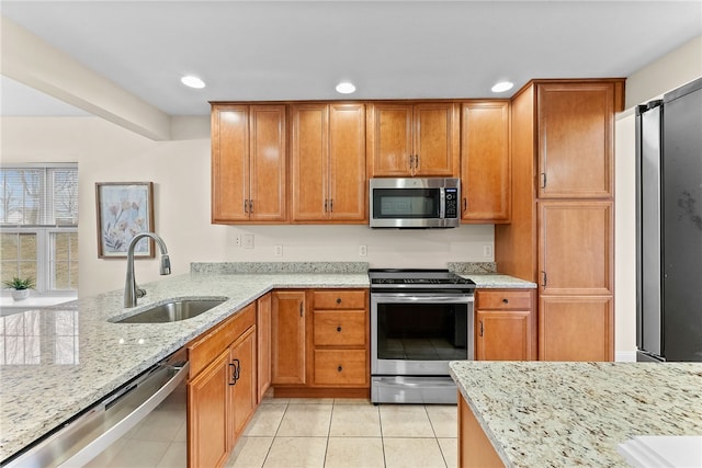 kitchen featuring stainless steel appliances, recessed lighting, light tile patterned flooring, a sink, and light stone countertops