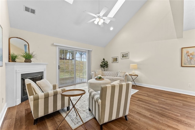 living area featuring a fireplace, visible vents, wood finished floors, high vaulted ceiling, and baseboards