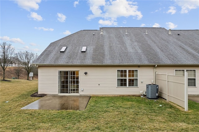 rear view of property with a shingled roof, central AC, a lawn, and a patio