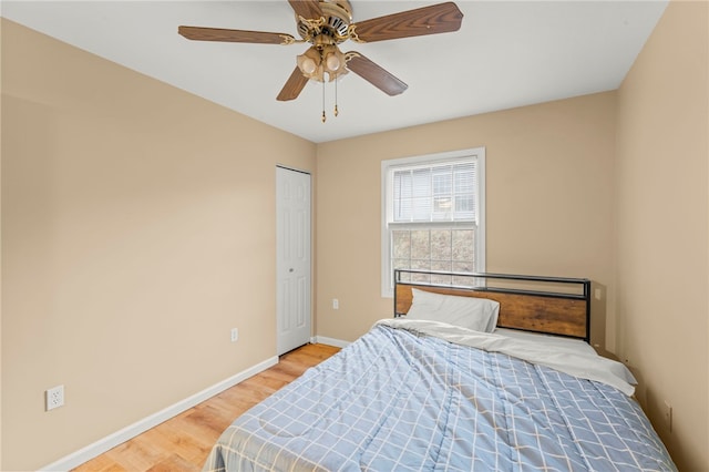 bedroom with a ceiling fan, light wood-style flooring, and baseboards