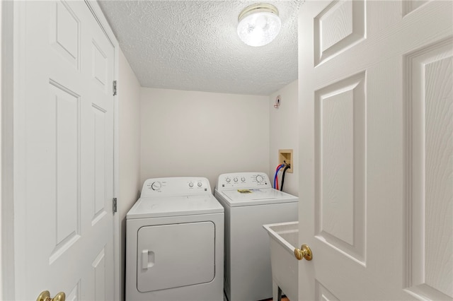 laundry area with a sink, laundry area, a textured ceiling, and independent washer and dryer