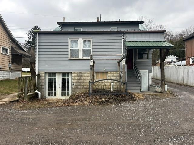 back of property with metal roof, french doors, and fence