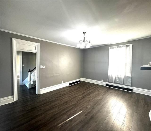 empty room featuring baseboards, a notable chandelier, wood finished floors, and crown molding