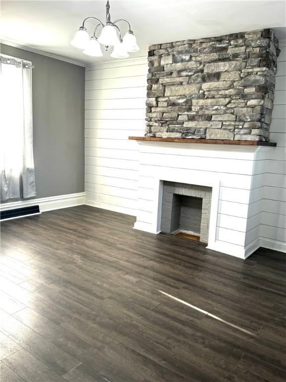 unfurnished living room with crown molding, a fireplace, dark wood finished floors, and an inviting chandelier