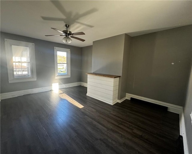 empty room with dark wood-style floors, ceiling fan, and baseboards