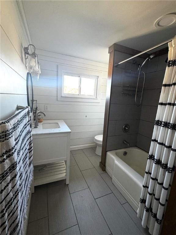 full bath featuring toilet, wood walls, shower / bath combination with curtain, and vanity