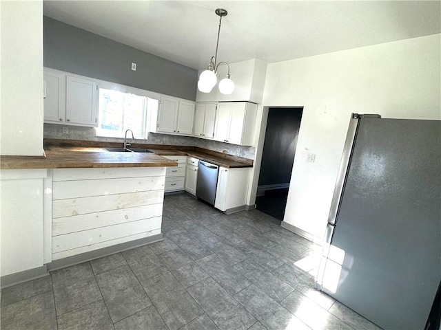 kitchen featuring butcher block counters, stainless steel appliances, white cabinetry, pendant lighting, and a sink