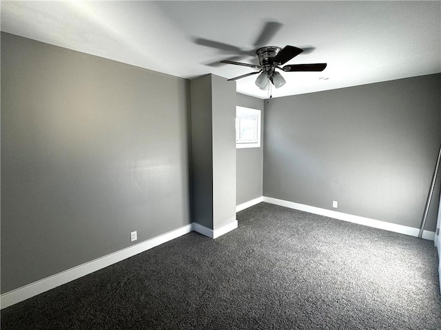 empty room with baseboards, dark carpet, and a ceiling fan