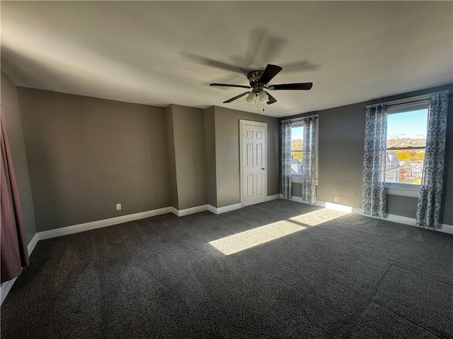 unfurnished room featuring dark carpet, a ceiling fan, and baseboards