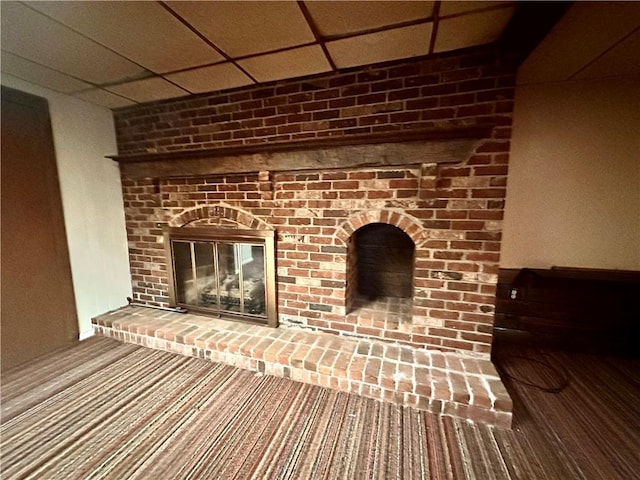details with a drop ceiling and a brick fireplace