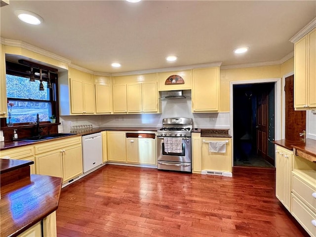 kitchen with dark wood finished floors, dark countertops, stainless steel gas range, white dishwasher, and a sink