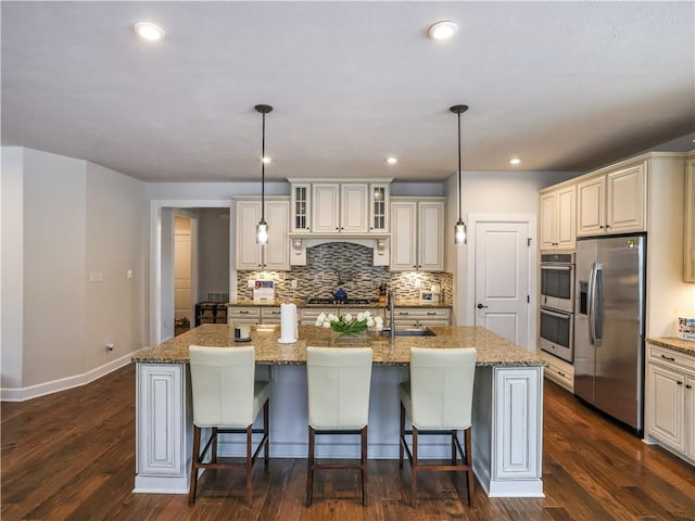 kitchen featuring backsplash, appliances with stainless steel finishes, a kitchen breakfast bar, and a kitchen island with sink