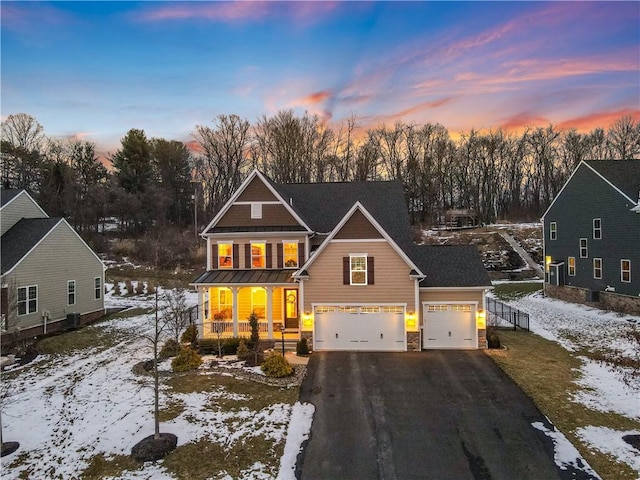 view of front of home featuring aphalt driveway, covered porch, and a standing seam roof