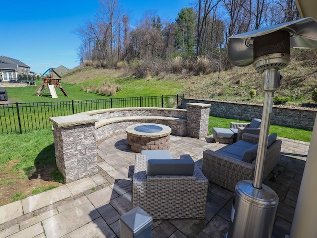 view of patio with fence, a fire pit, and a playground