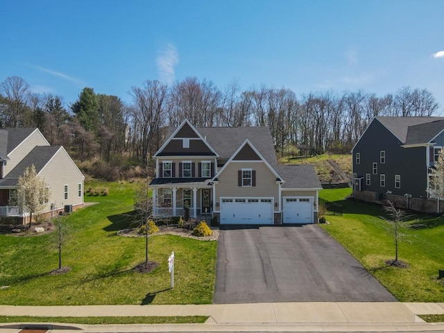 view of front of home featuring an attached garage, a porch, a front lawn, and aphalt driveway