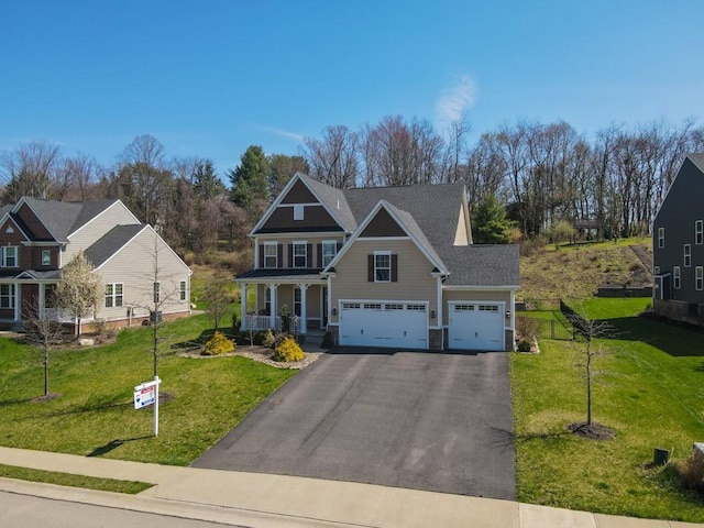 craftsman-style house with driveway, a porch, and a front yard