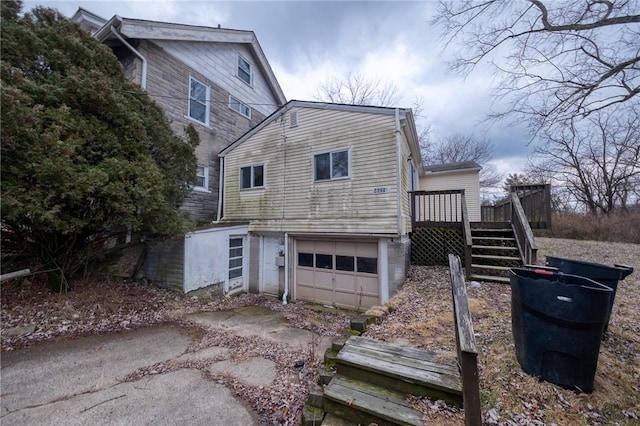 exterior space with driveway, stairway, an attached garage, and a wooden deck