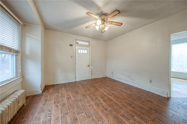 empty room with radiator, a textured ceiling, and wood finished floors