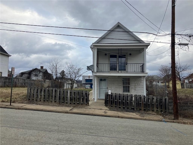 view of front facade featuring a fenced front yard, covered porch, and a balcony