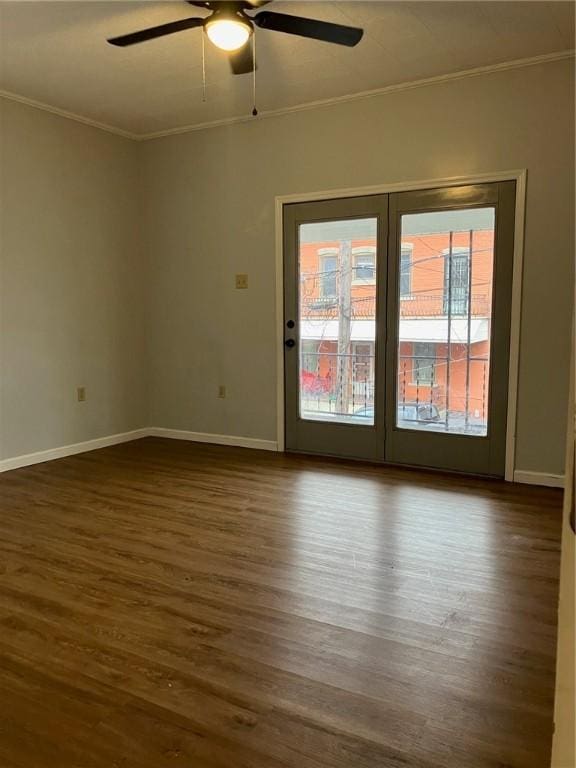 empty room with baseboards, dark wood-style flooring, and crown molding