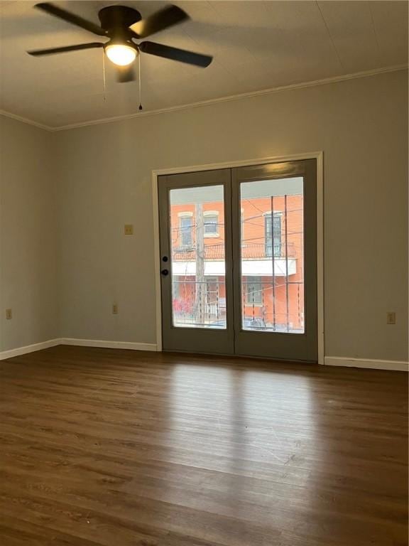 empty room with dark wood-style floors, ornamental molding, and baseboards